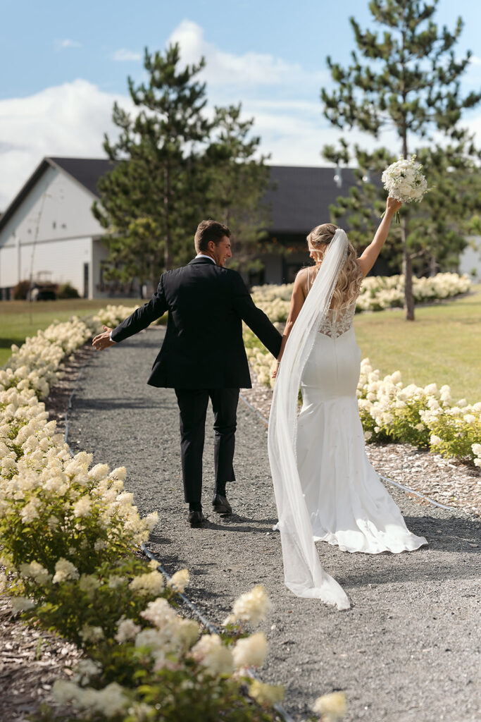 romantic bride and groom walking towards their venue in bluebelle event venue, bemidji, mn