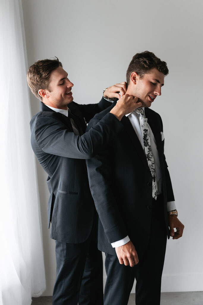 groom getting ready next to a large window inside the bluebelle event venue