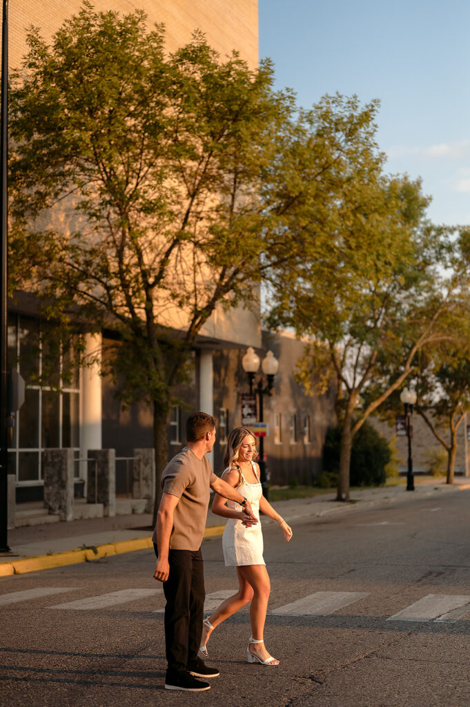 sweet couple walking around during golden hour for their downtown engagement photos in Bemidji