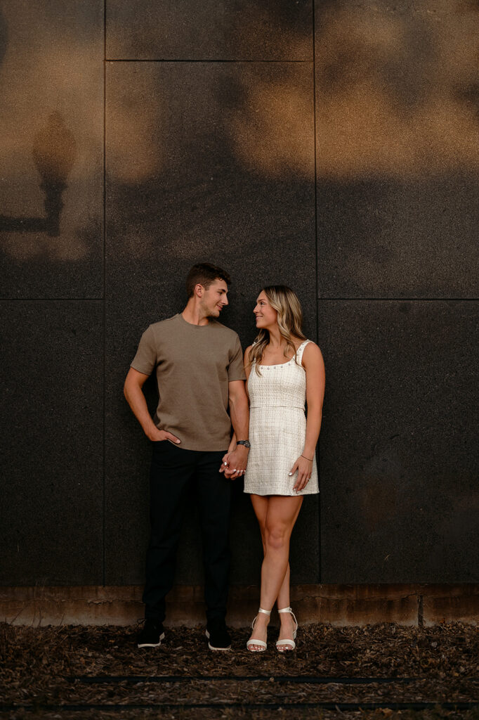 sweet couple posing in front of a dark wall during downtown engagement photos in Bemidji