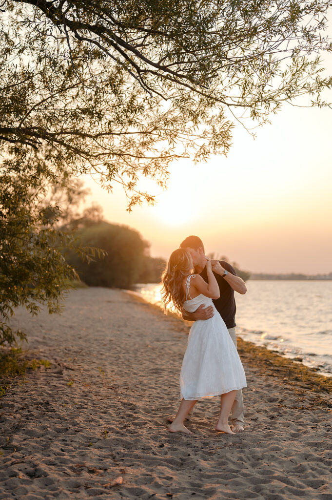 couple being sweet and playful during sunset on Lake Bemidji shore