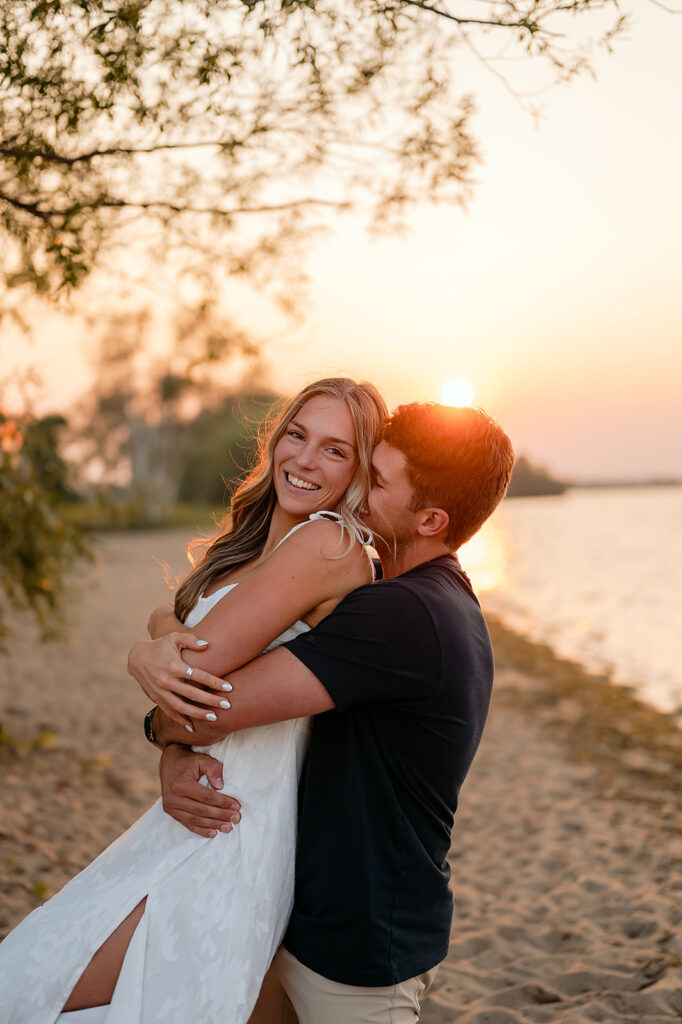 couple being sweet and playful during sunset on Lake Bemidji shore