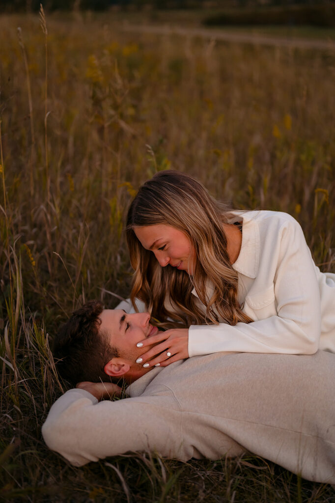 couple laying down together in a lush golden field