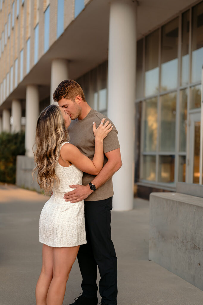 sweet couple kissing during golden hour for their downtown engagement photos in Bemidji