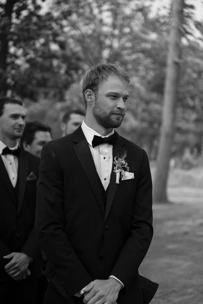 groom waiting at the end of the aisle during lakeside wedding ceremony set up overlooking Lake Bemidji