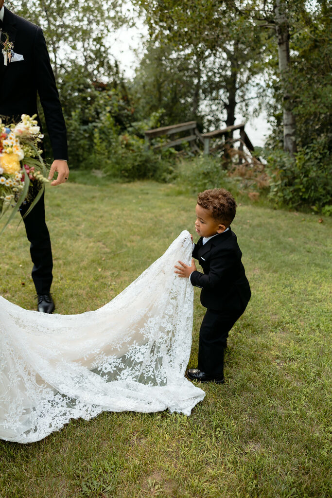 cute little boy holding brides dress