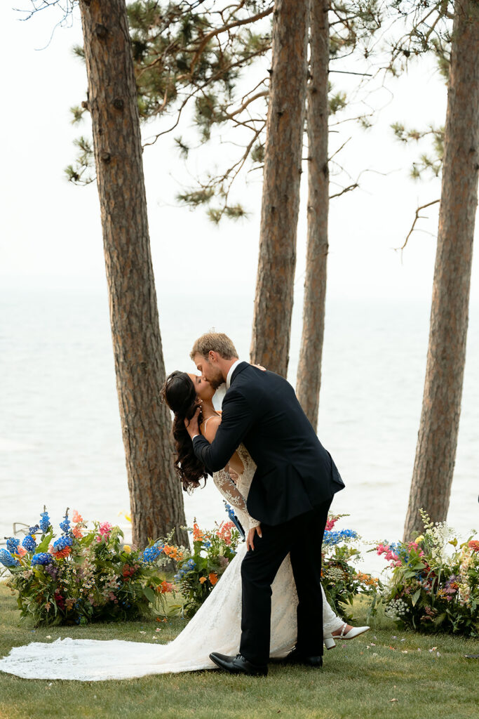 bride and groom kissing during a lakeside wedding ceremony set up overlooking Lake Bemidji