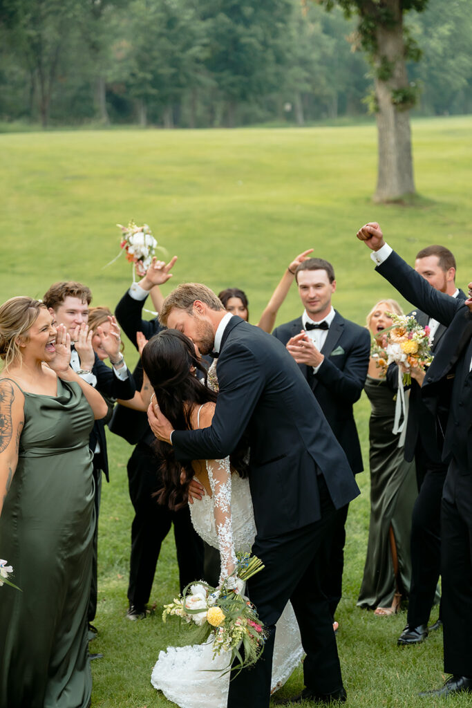 fun bride and groom with their wedding party surrounding them and cheering