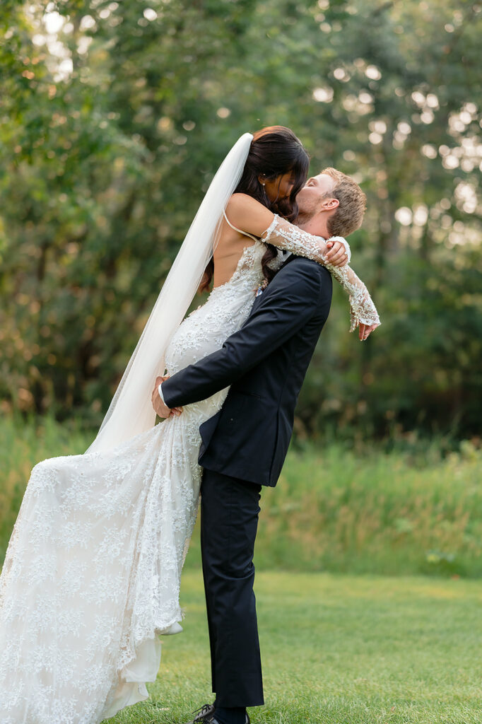 bride and groom kissing surrounded by lush green landscapes during their lakeside wedding in bemidji mn