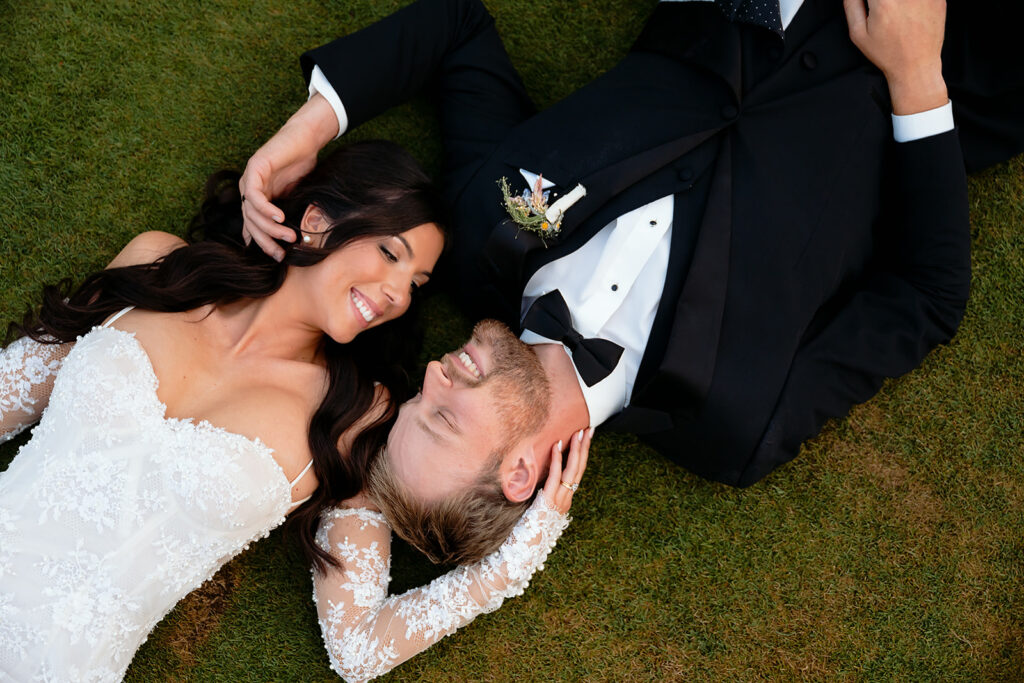 bride and groom laying down in the grass together