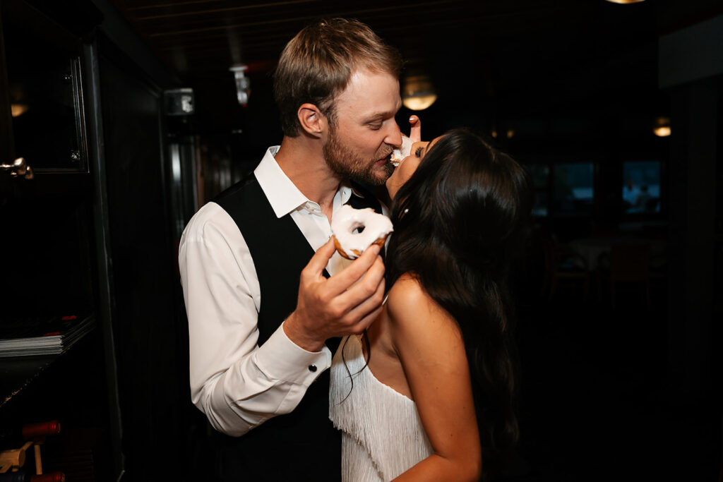bride and groom sharing a doughnut together