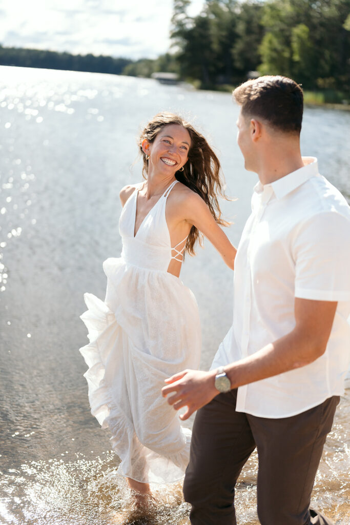 playful couple running in the lake during their romantic Catalyst By Nature Link engagement session
