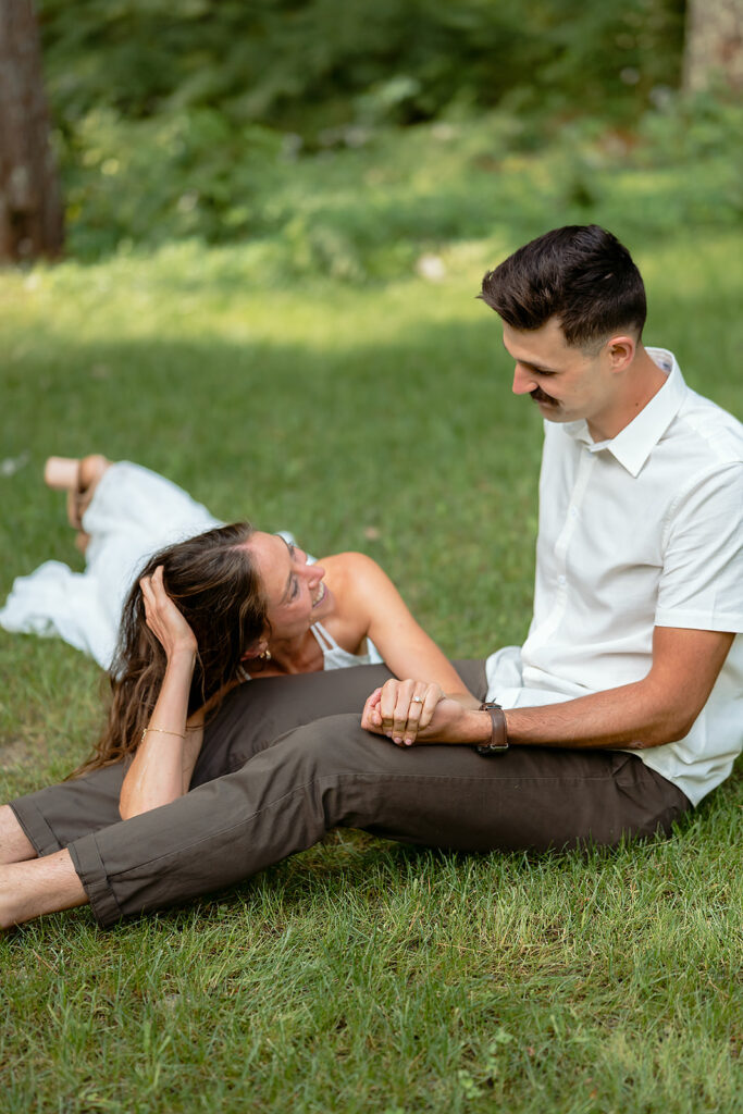 sweet couple sitting in the grass together surrounded by forest