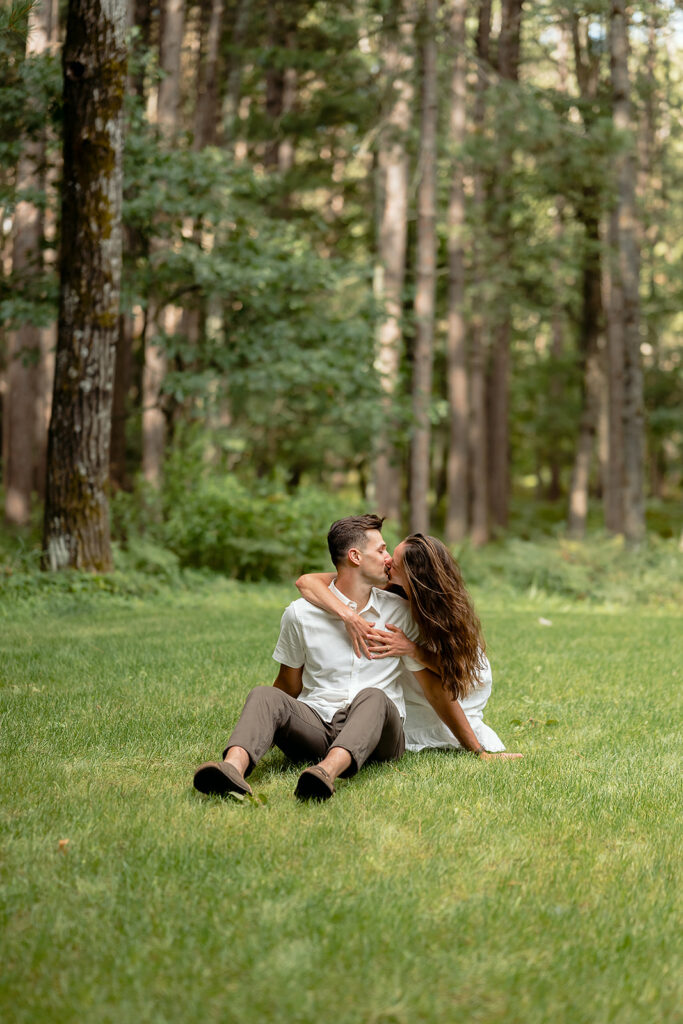 sweet couple sitting in the grass together surrounded by forest