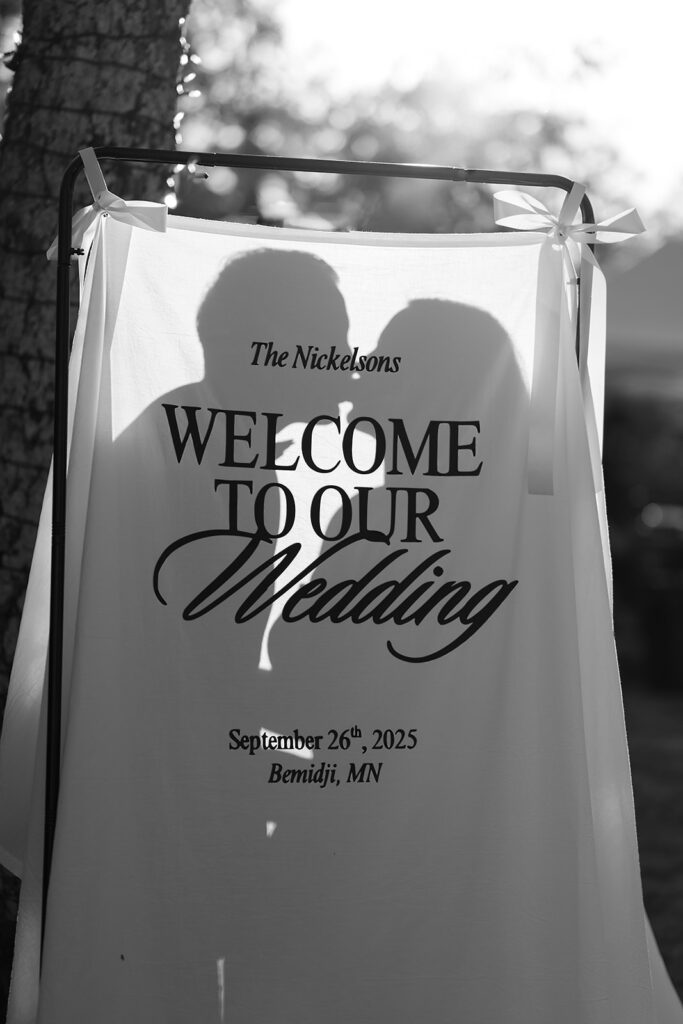 bride and groom kissing behind their welcome sign