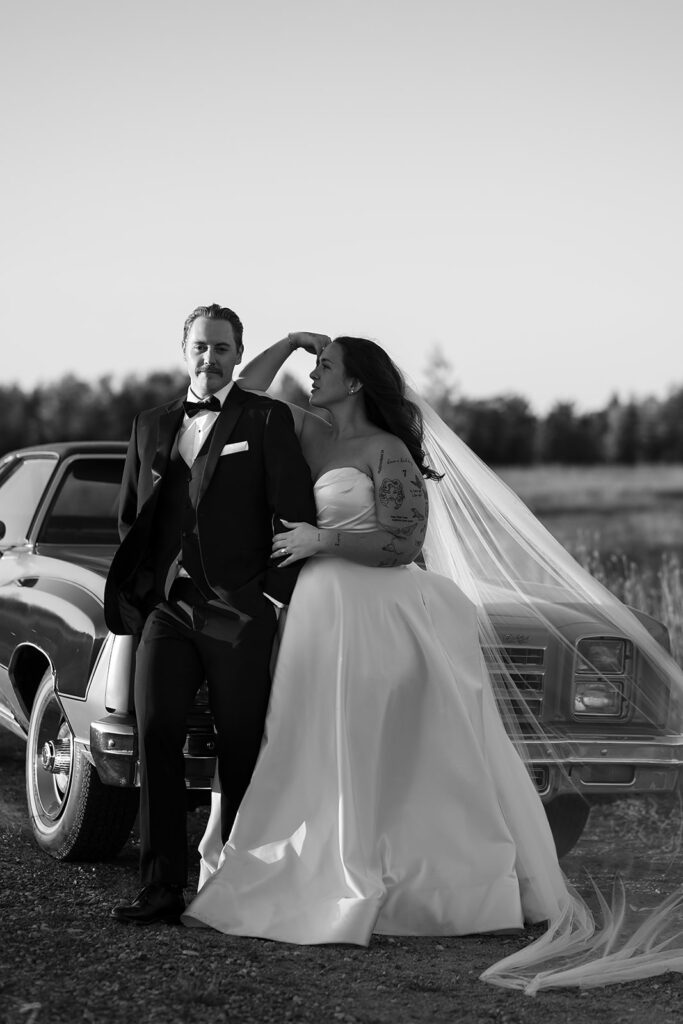 playful golden hour wedding portraits in a lush field with their vintage getaway car