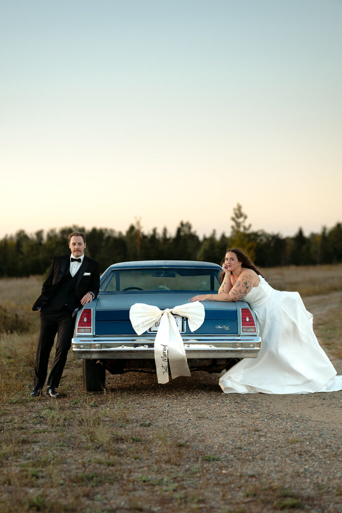 bride and groom posing next to their vintage blue chevy getaway car