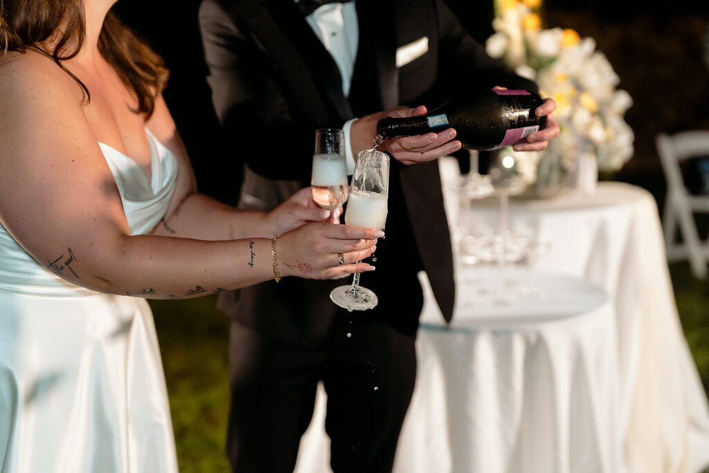 bride and groom popping champagne and pouring a champagne tower