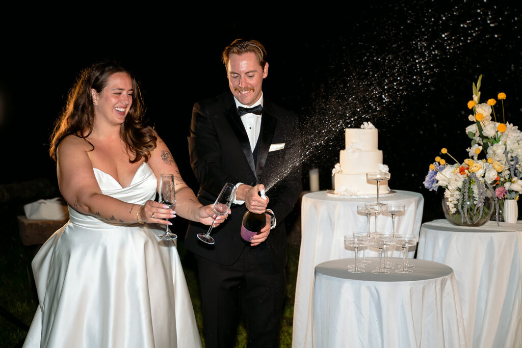 bride and groom popping champagne and pouring a champagne tower