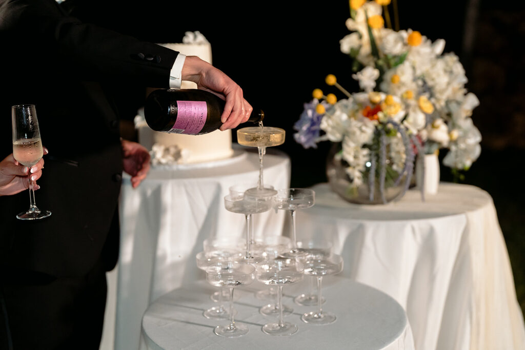 bride and groom popping champagne and pouring a champagne tower