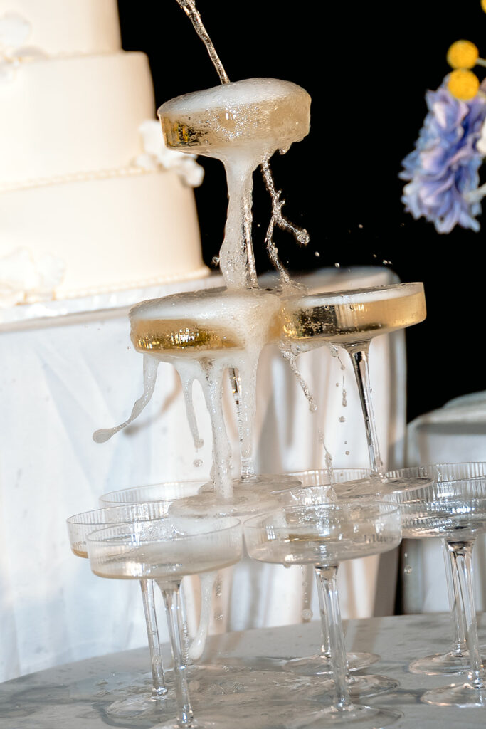 bride and groom popping champagne and pouring a champagne tower