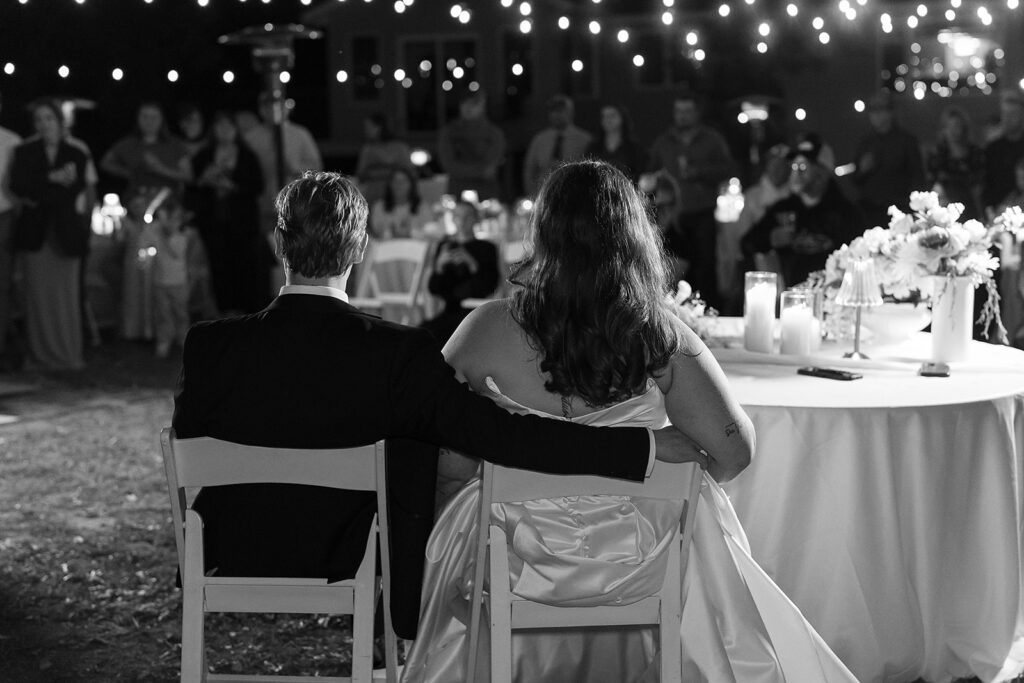 bride and groom listening to toasts during their backyard wedding reception
