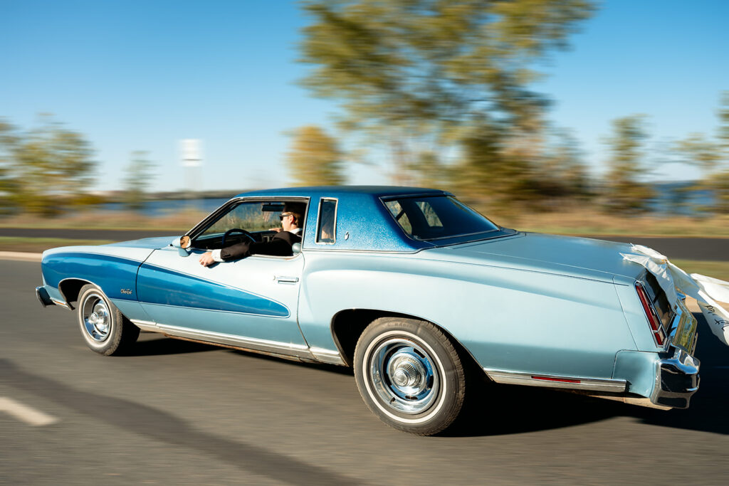bride and groom driving off into a vintage blue chevy getaway car