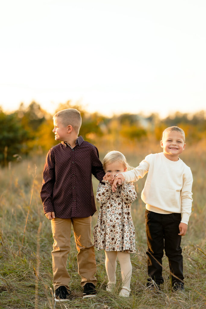 three kiddos in a lush golden field