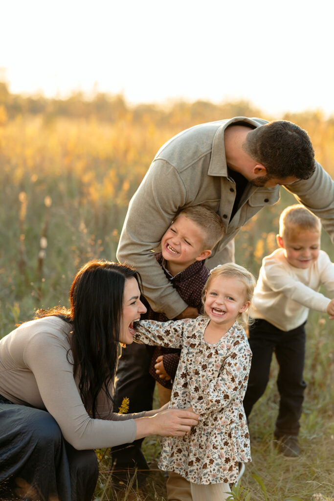 fall family photography of mom, dad and their two sons and little daughter in a golden field