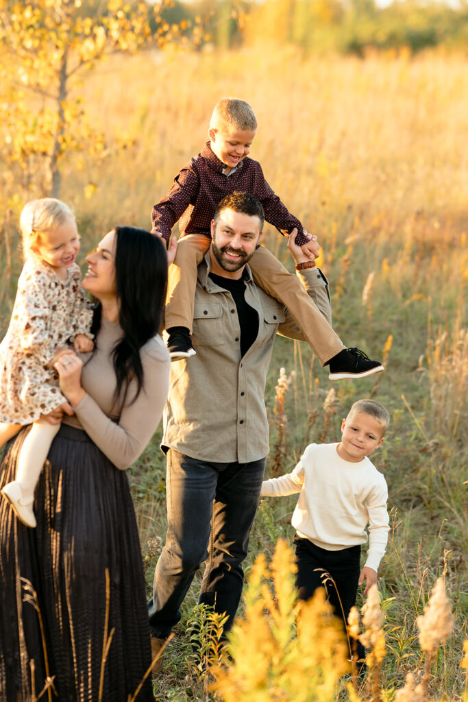fall family photography of mom, dad and their two sons and little daughter in a golden field