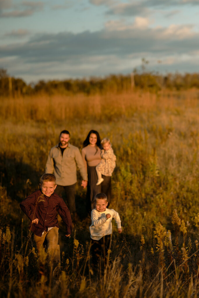fall family photography of mom, dad and their two sons and little daughter in a golden field