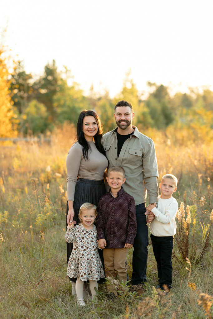 fall family photography of mom, dad and their two sons and little daughter in a golden field