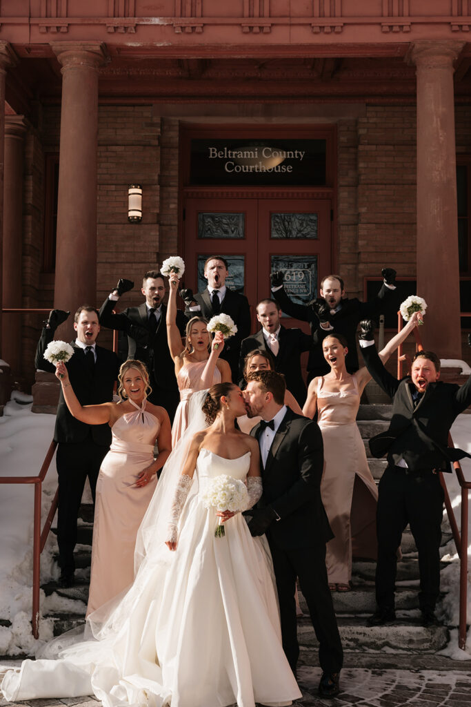 wedding couple and their wedding party during a winter wedding in front of the Beltrami County Courthouse