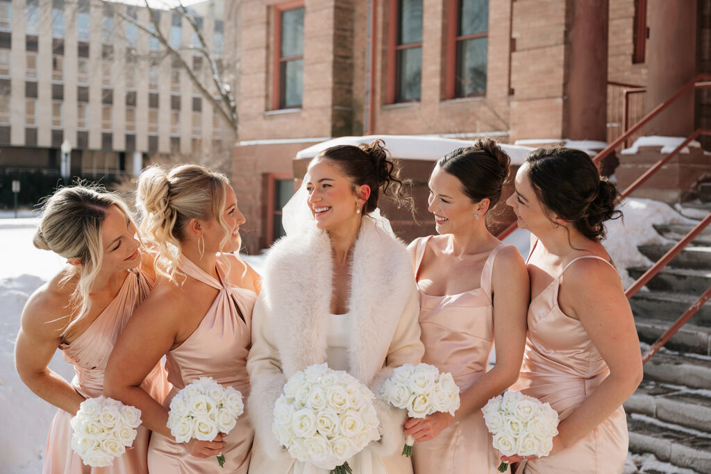 bride and bridesmaids during a winter wedding in front of the Beltrami County Courthouse