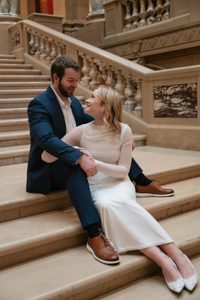 couple sitting on marble staircase during Minnesota State Capitol engagement photos
