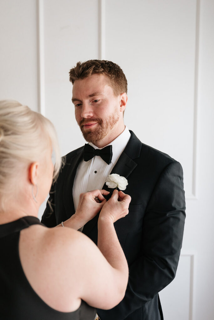 mom helping groom with his boutonniere