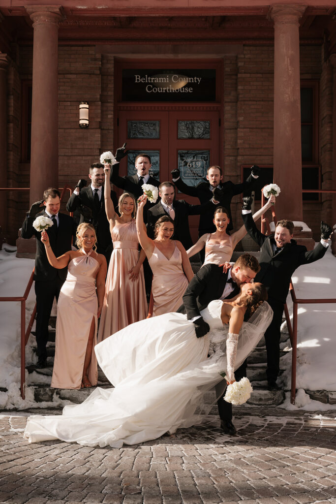 wedding couple and their wedding party during a winter wedding in front of the Beltrami County Courthouse