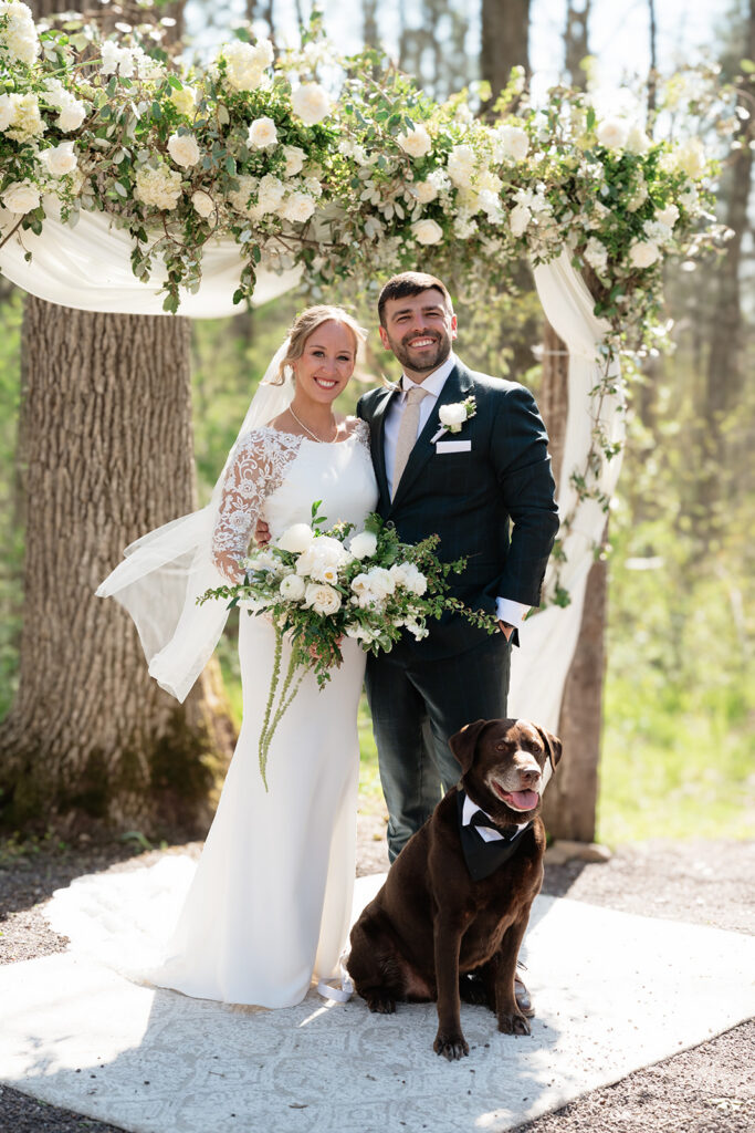 bride and groom with their pup at the outdoor ceremony space of The Atrium in Solon Springs, Wisconsin