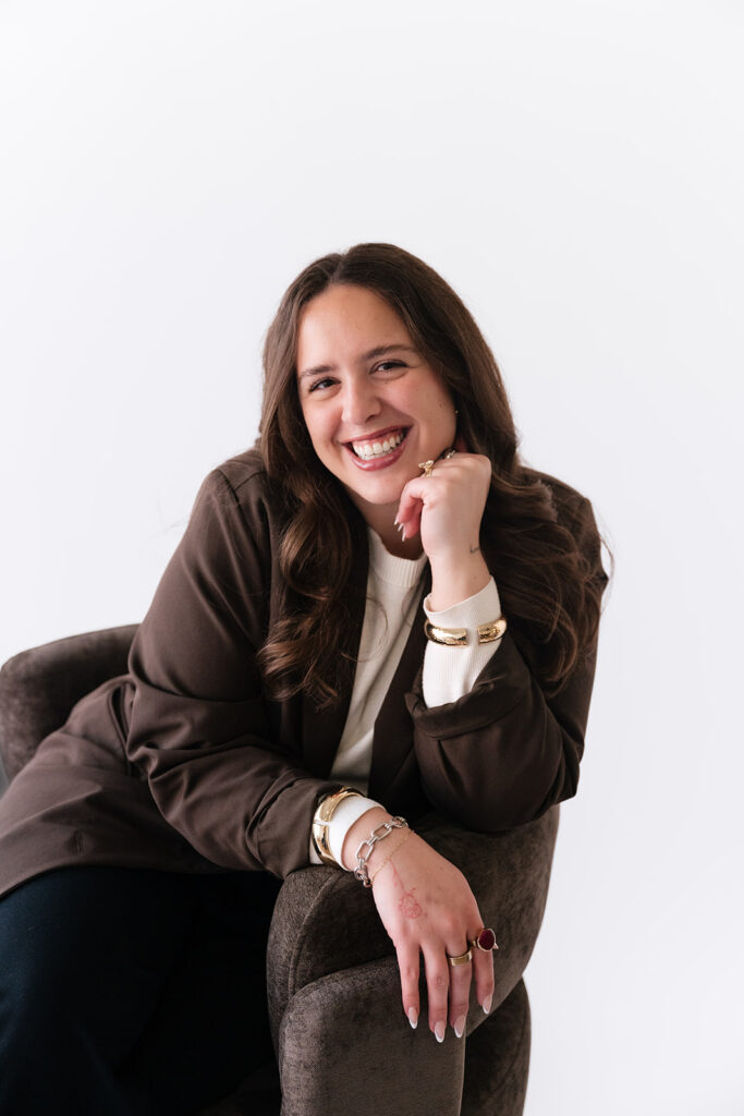 Smiling creative entrepreneur posing in a brown blazer during her studio brand photography session.