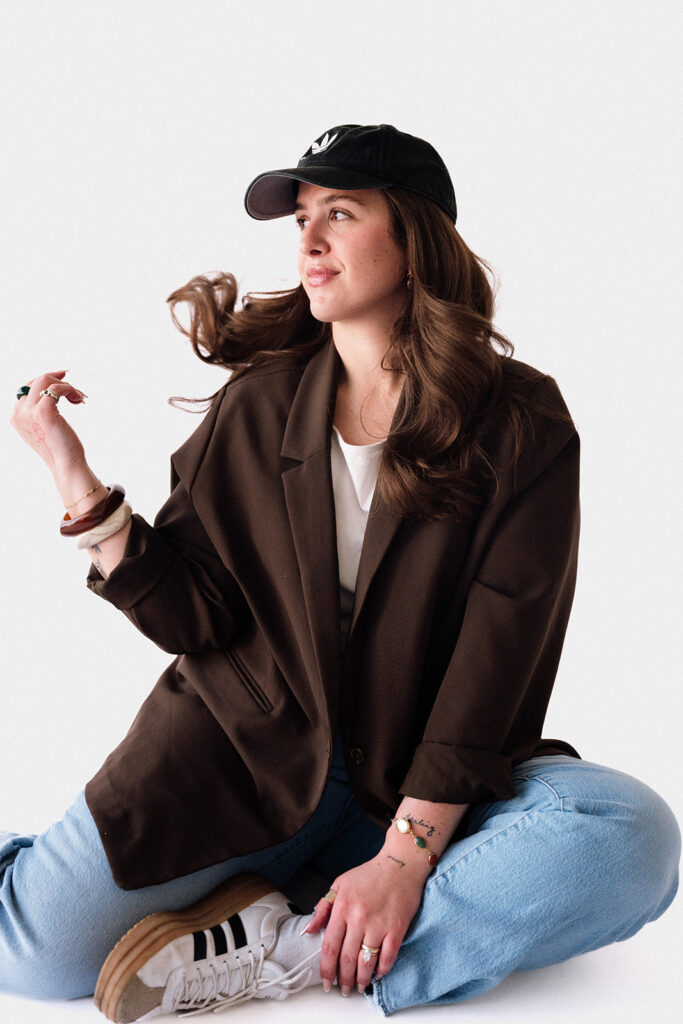 Smiling creative entrepreneur posing in a brown blazer during her studio brand photography session.