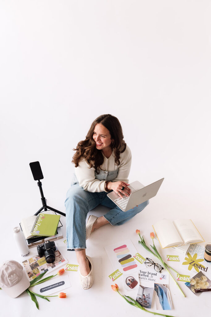 Brand photographer’s content creation setup with a phone tripod, coffee, notebooks and business books.