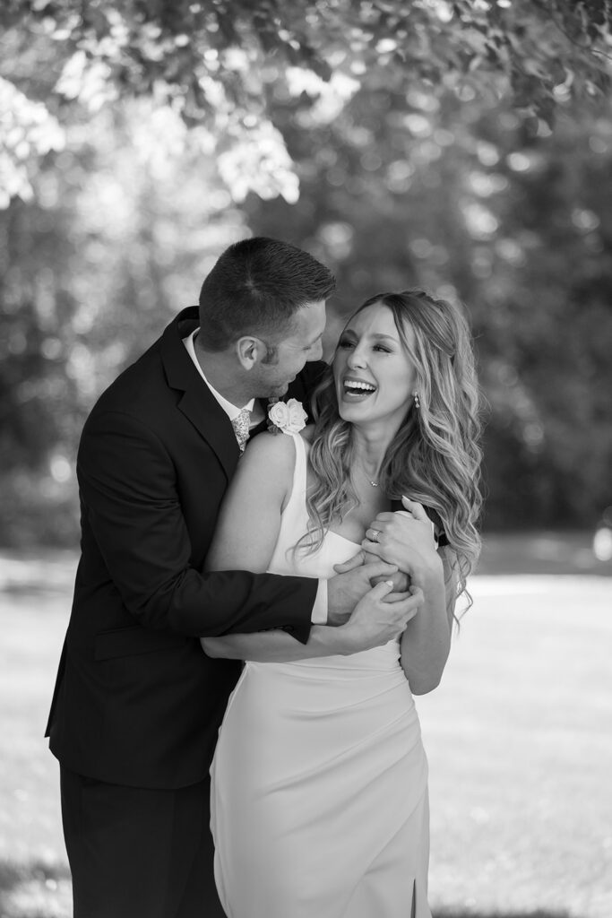 Bride and groom embracing in a grassy field at their Freeport, Minnesota small town wedding