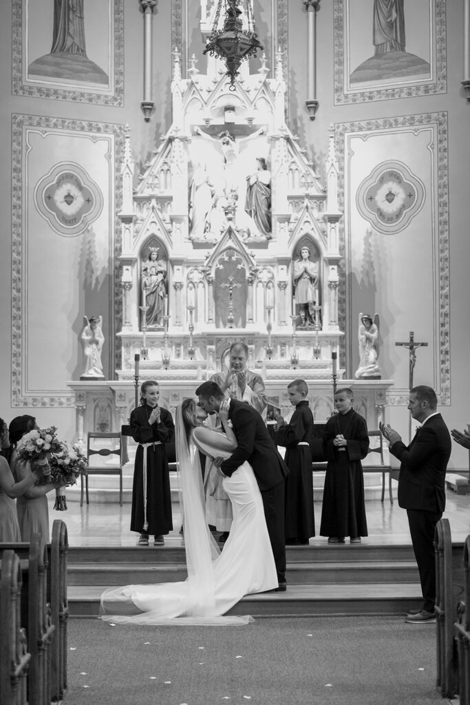 first kiss as newlyweds at the ceremony at Sacred Heart Catholic Church