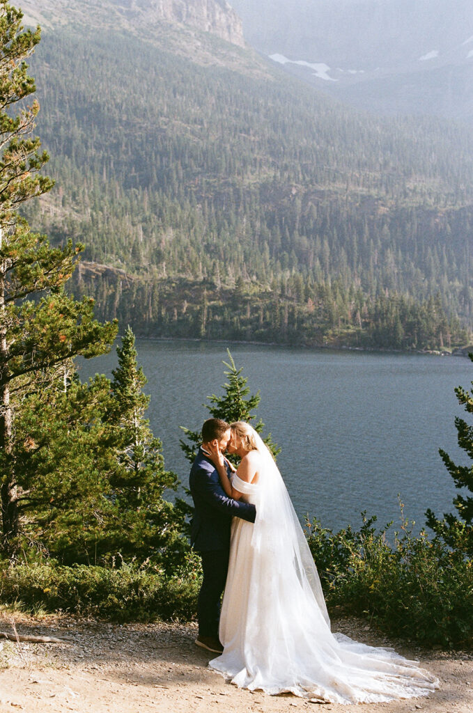 bride and groom kissing at glacier national park with mountain views in the backdrop