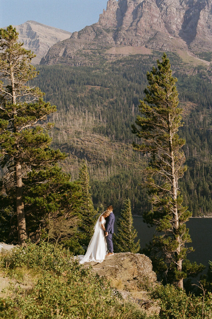bride and groom hugging at glacier national park with mountain views in the backdrop