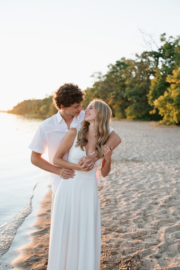 playful couple at the beach of lake bemidji during sunset