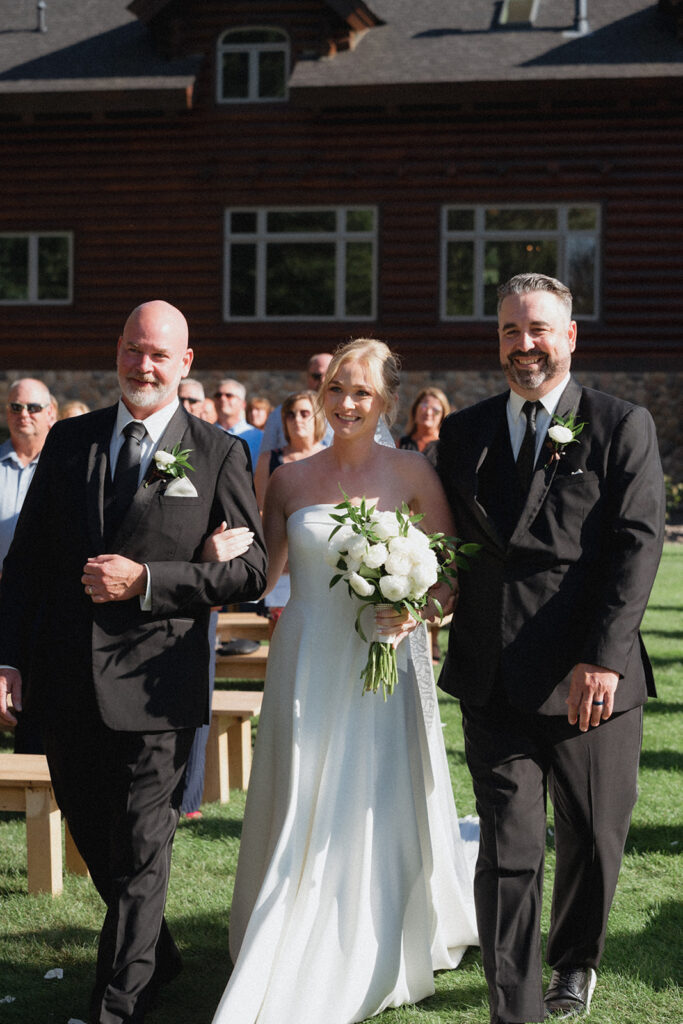 bride walking down the aisle with her dads